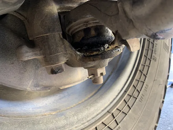 Ball joint dust boot tear and contamination damage Torn ball joint dust boot causing contamination and accelerated wear