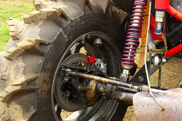 Off-road vehicle with heavy load driving on rough terrain showing suspension compression